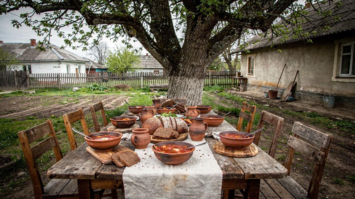 Wooden farm table in a village courtyard laid for a shared Saturday lunch
